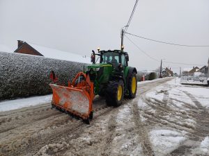 Tracteur avec une lame de déneigement en action à Ohey